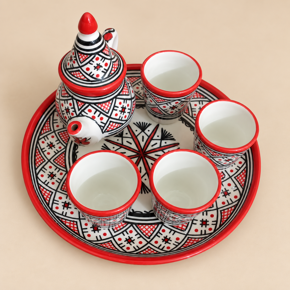 Moroccan ceramic teapot with four cups and a round tray, decorated with black-and-white geometric patterns and red rims